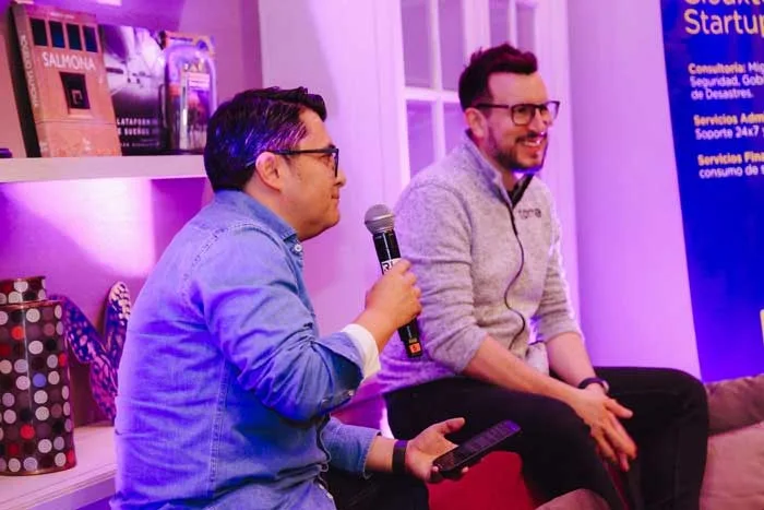 Alexander Torrenegra ríe durante un fireside chat mientras el anfitrión habla al micrófono.
